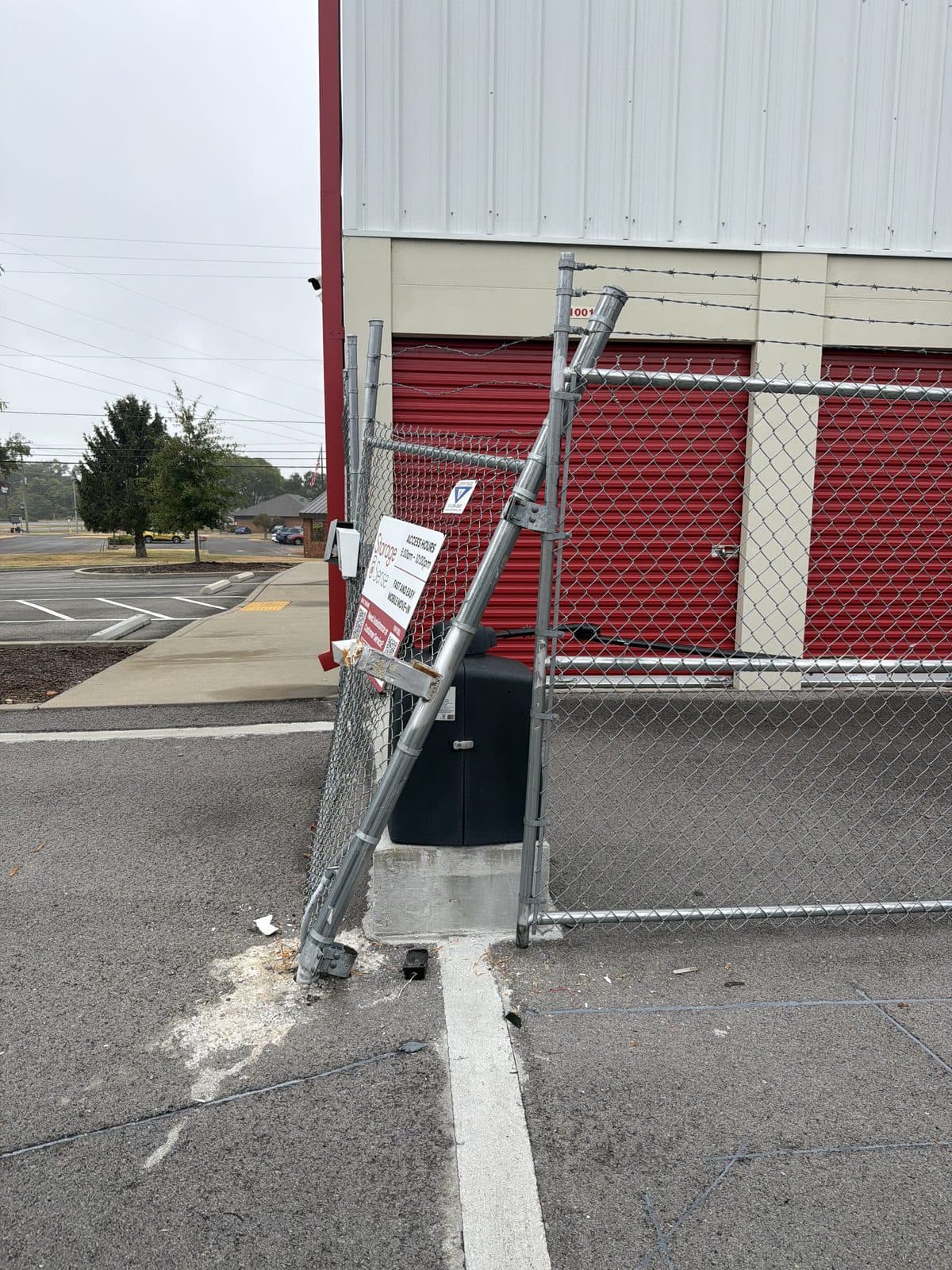 Chain link fence post knocked over by a moving truck beside the gate opener at Storage Sense, La Vergne, TN