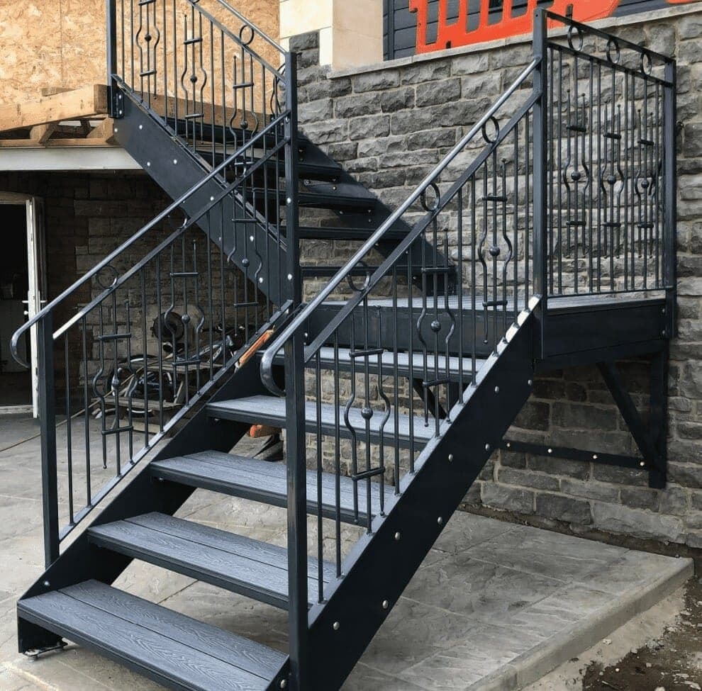 Exterior steel steps with metal handrails beside a brick building