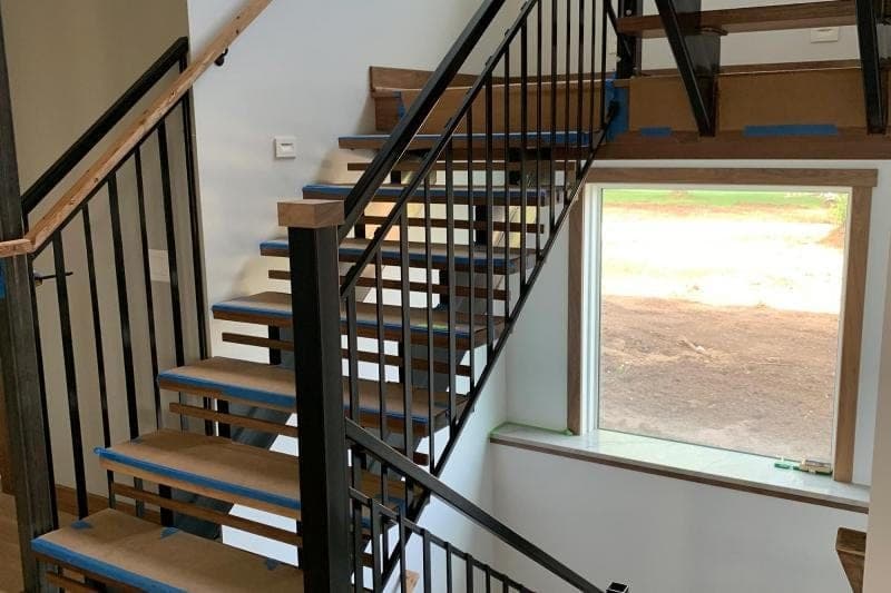 Open-riser interior staircase with wood treads and dark metal railings