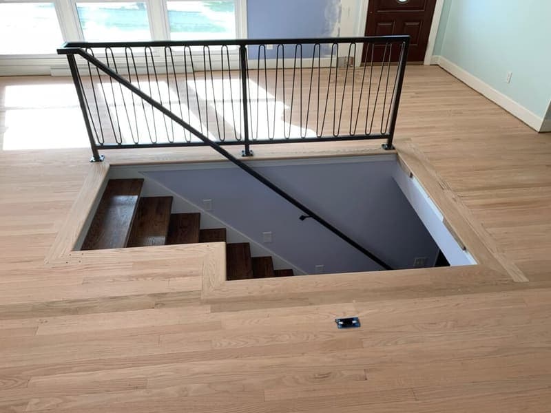 Metal railing around an interior stair opening with looped balusters